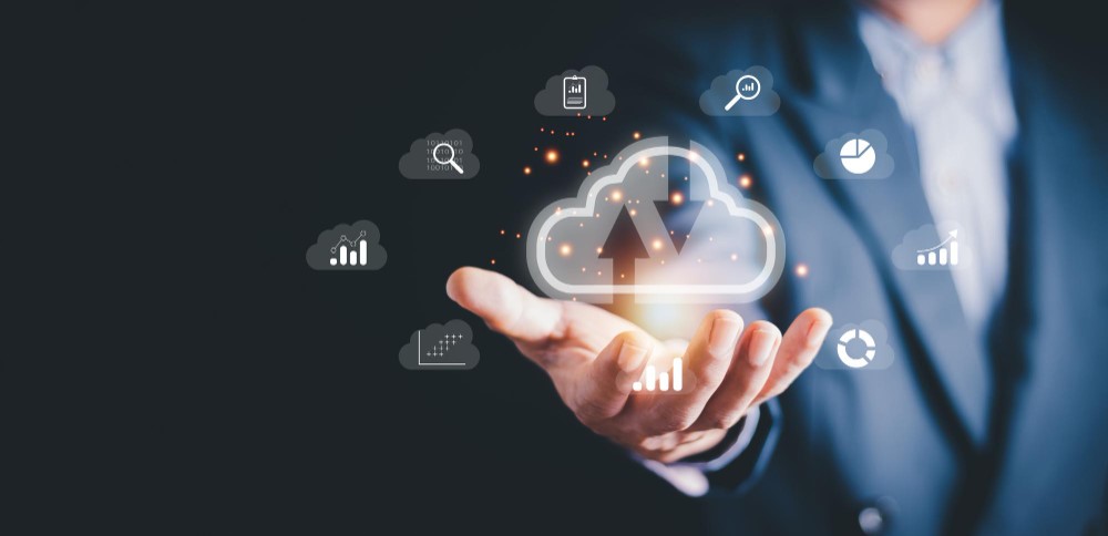Hand in a suit holding glowing cloud and chart icons