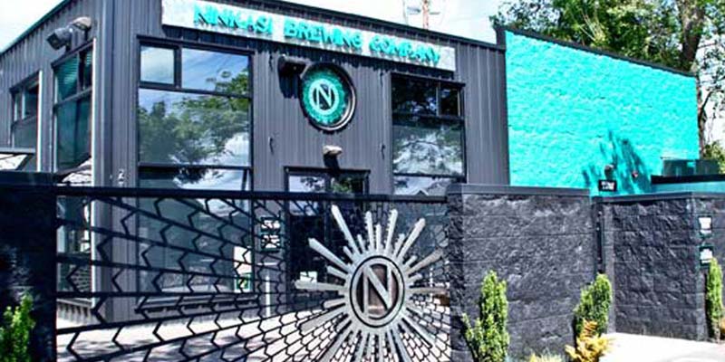 Ninkasi Brewing gray building with a teal wall and sunburst gate