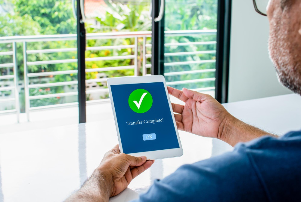 Man holding a tablet that says Transfer Complete with a green check