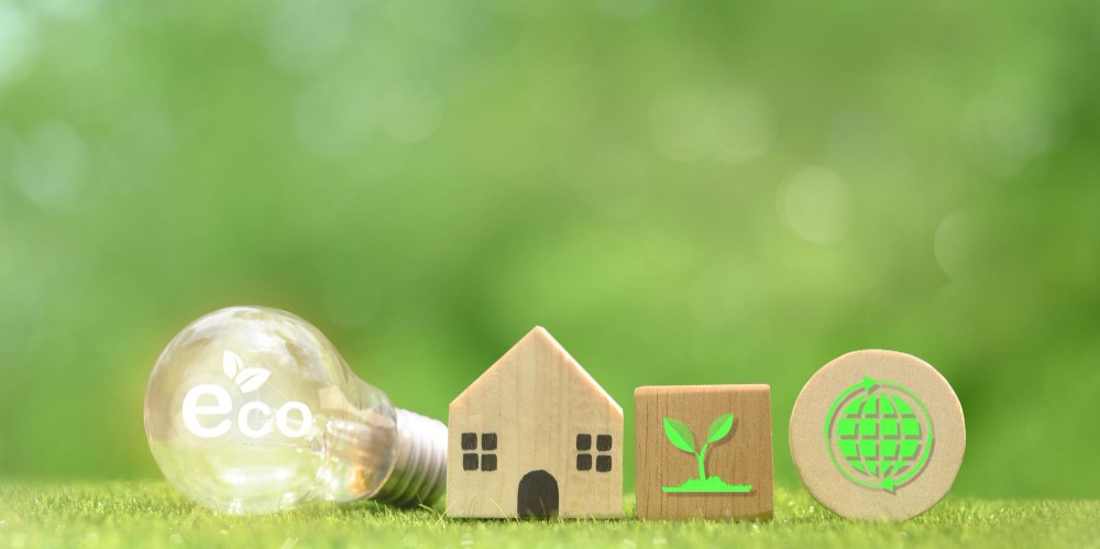 Eco lightbulb, wooden house, plant, and globe on grass