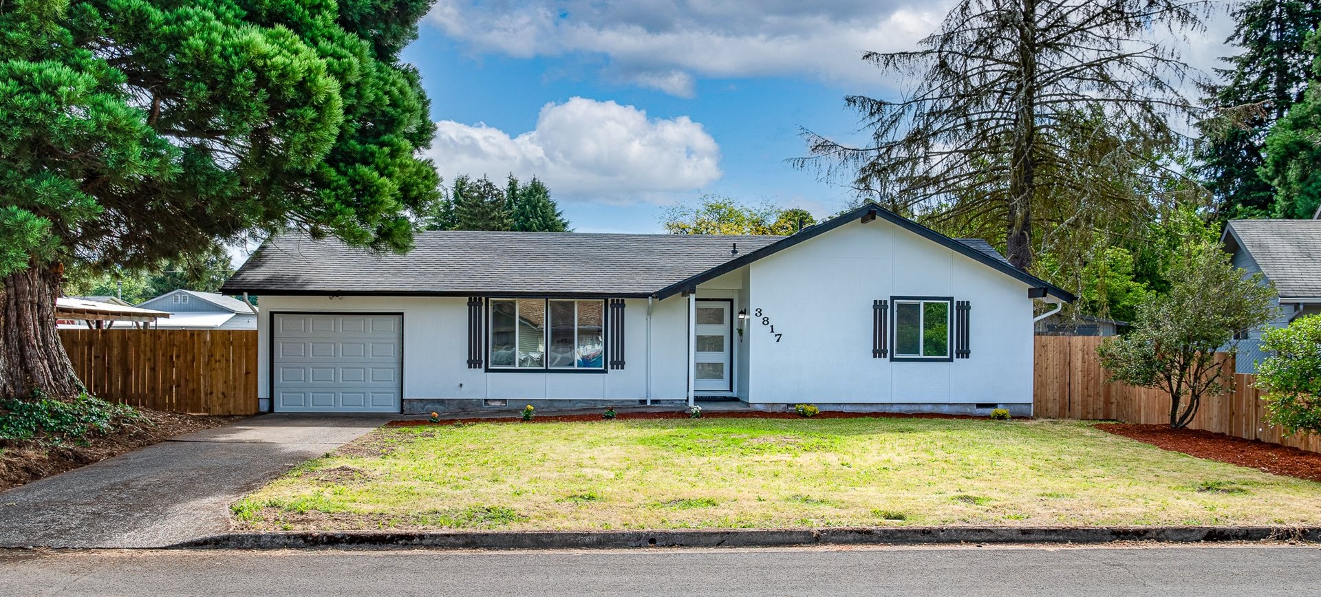 White ranch house numbered 3817 with black shutters and a gray garage door