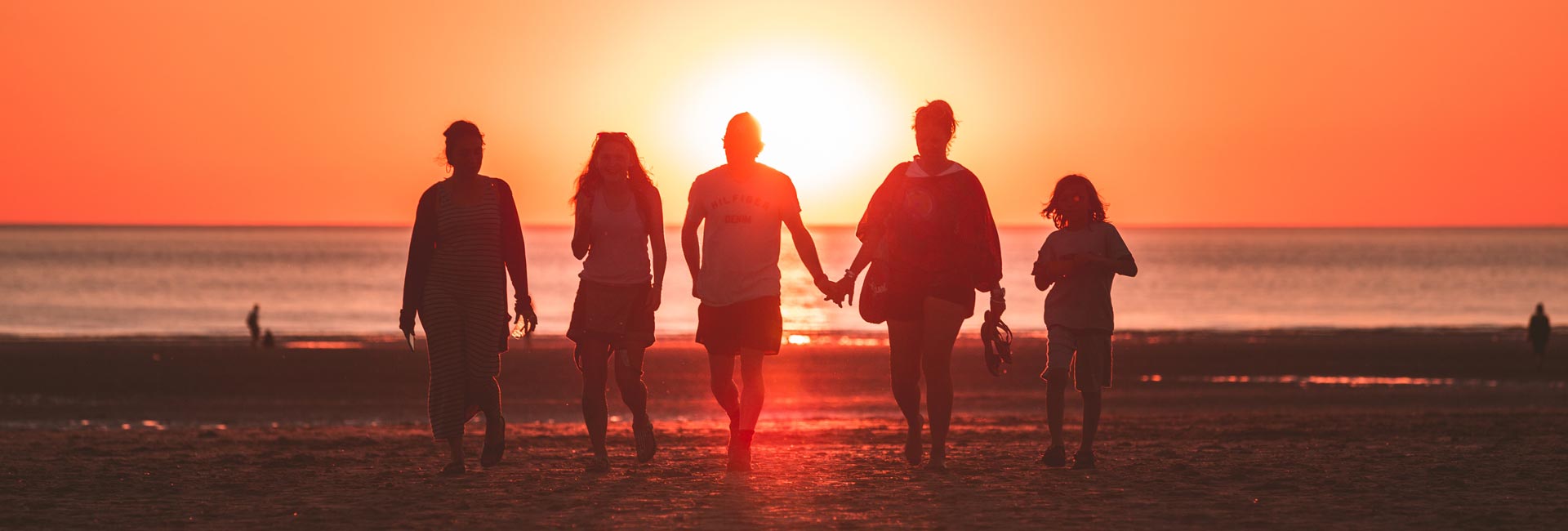 Family walking on a beach at sunset