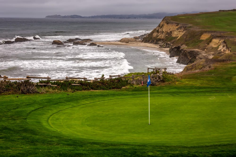 Coastal golf green with a blue flag above ocean cliffs