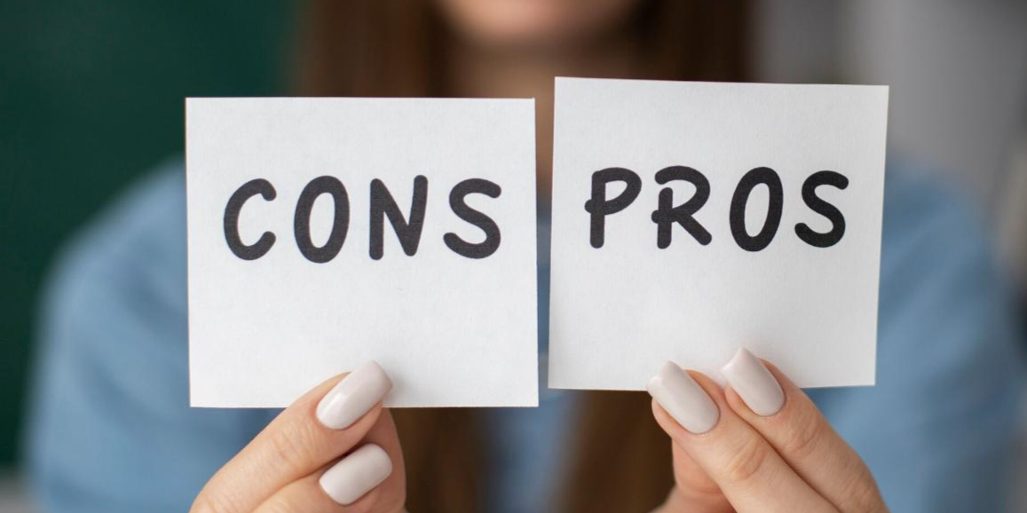 Hands holding two cards that say Cons and Pros