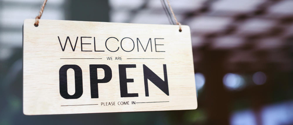 Wooden sign that reads Welcome We Are Open Please Come In