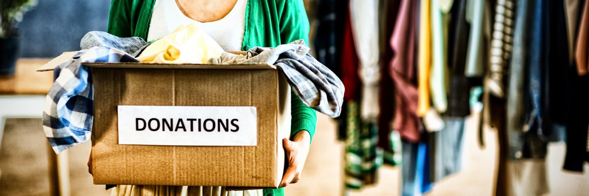 Person holding a cardboard box labeled Donations