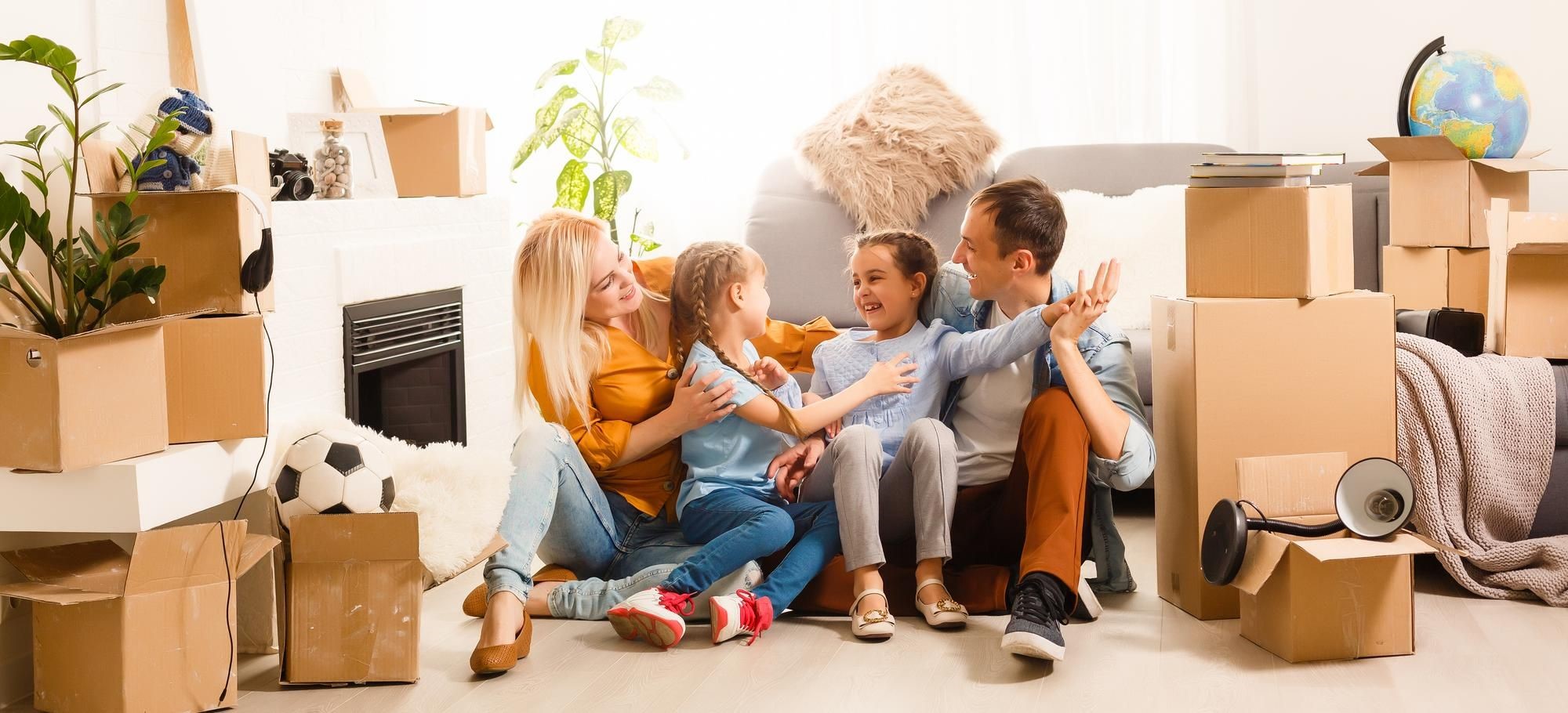 Family sitting on the floor among moving boxes in a living room