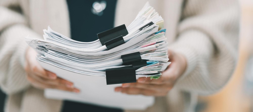 Hands holding a thick stack of clipped papers