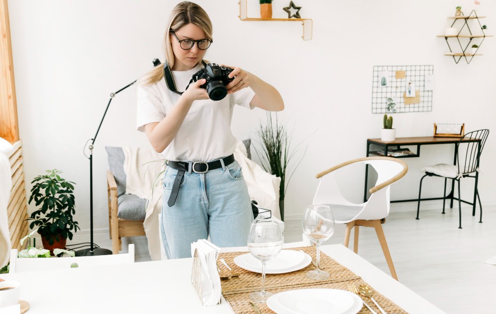 Woman photographing a set dining table in a bright room