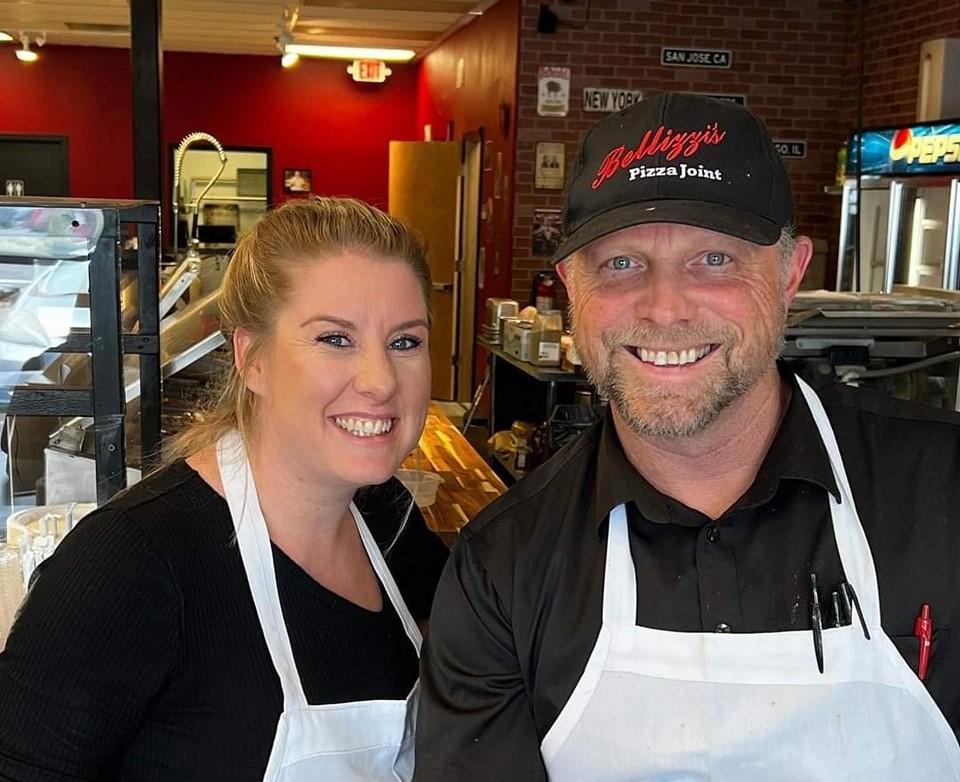 Two people in aprons; man wearing a Bellizzi's Pizza Joint hat