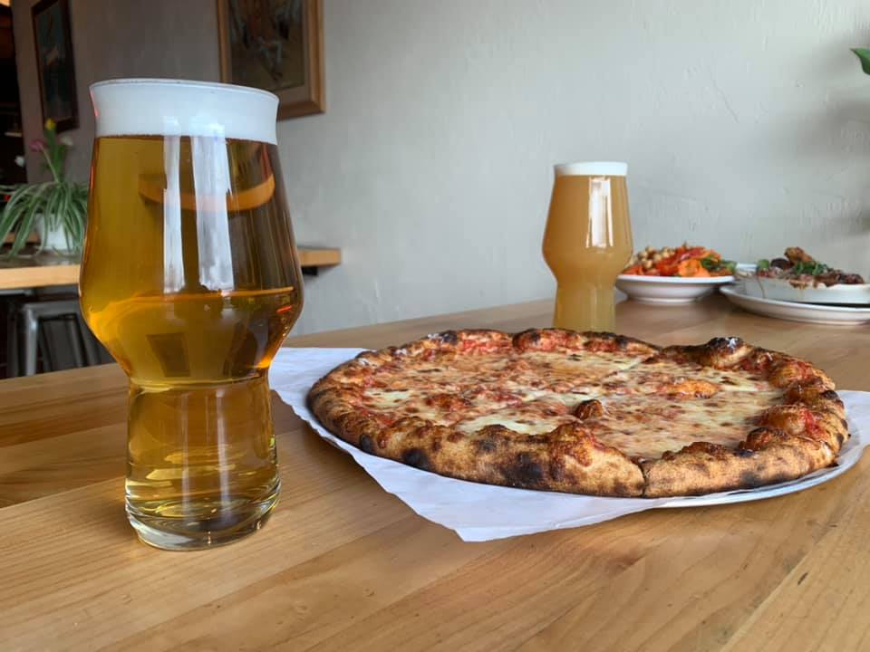 Cheese pizza and two beers on a wood table