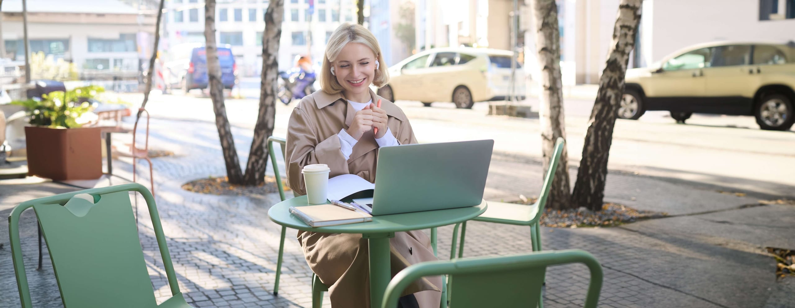 Woman with a laptop and coffee at an outdoor cafe table