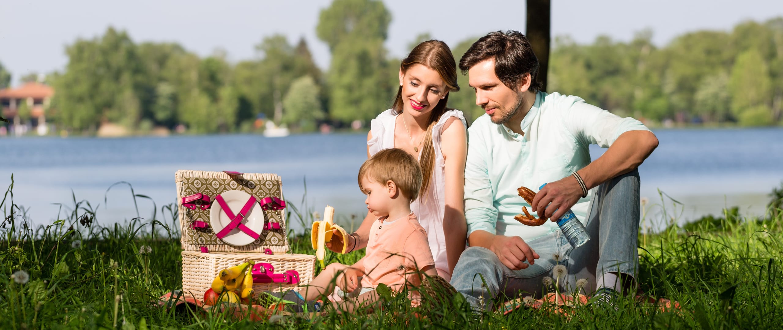 Family picnicking by a lake with a child