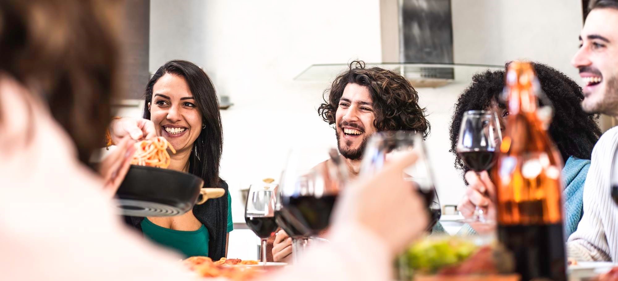 Friends sharing pasta and wine at a restaurant table
