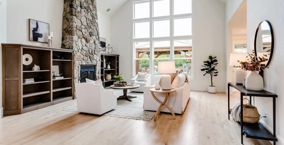 Staged living room with a stone fireplace and tall windows