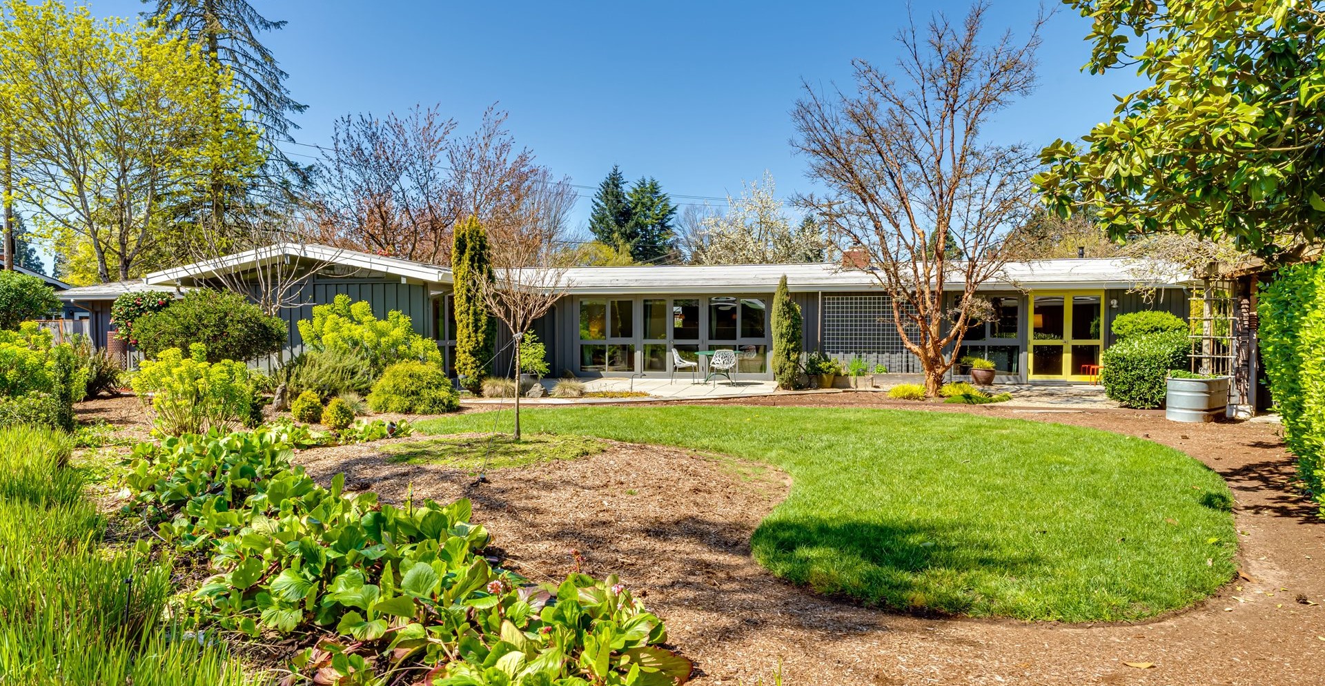 Low mid-century home with a wall of windows and a garden