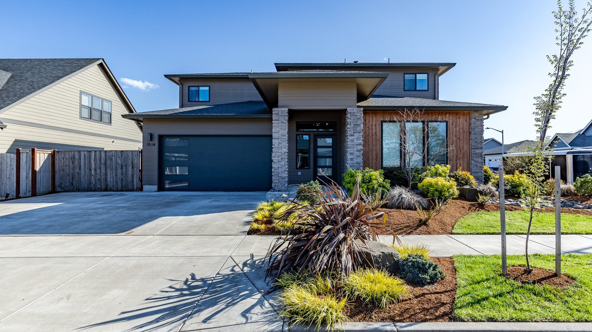 New two-story home with wood siding, stone columns, and a dark garage