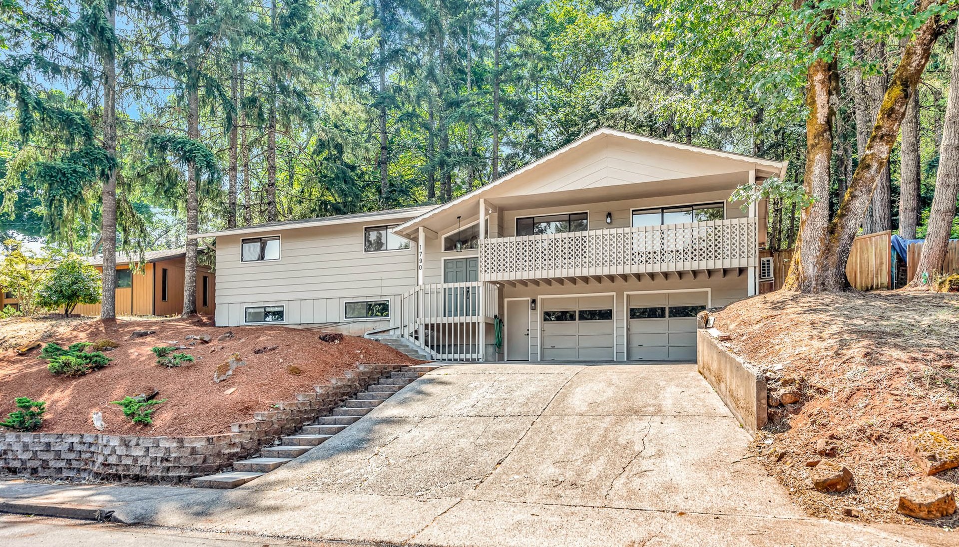 Split-level home with a balcony and two garage doors on a wooded lot