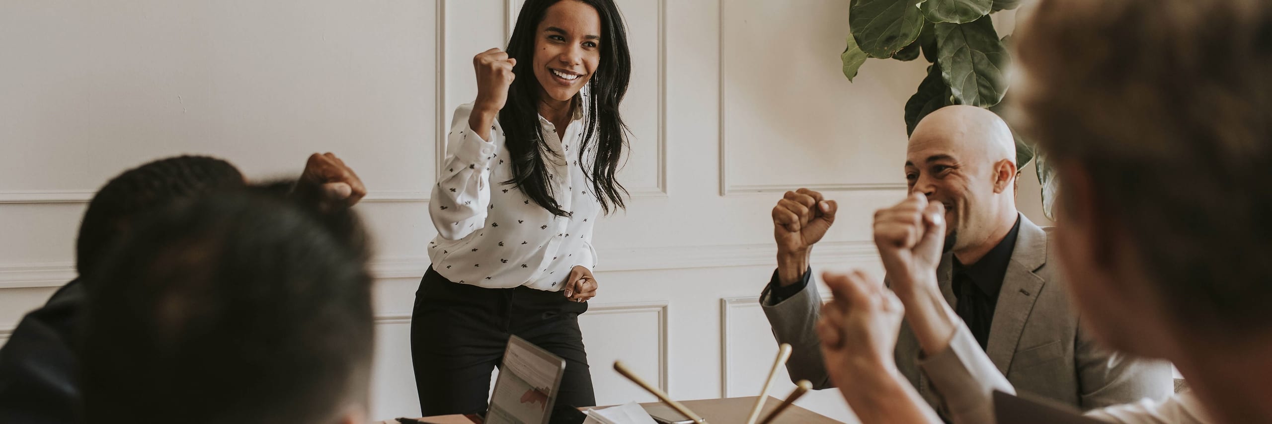 Woman and coworkers pumping fists around a conference table
